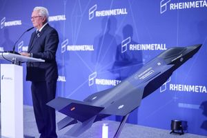 Ein Modell des F-35 auf der Bühne, auf der Konzernchef Papperger zu Mitarbeitern spricht. - Foto: Oliver Berg/dpa
