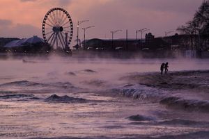 Menschen spazieren in Chicago über einen mit Eis bedeckten Strand am Ufer des Michigansees. - Foto: Kiichiro Sato/AP/dpa