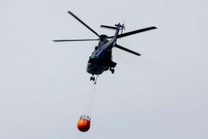 Ein Löschhubschrauber der Bundespolizei fliegt über dem Zeithainer Tagebau und nimmt Wasser auf, um den Waldbrand Gohrischheide zu bekämpfen. - Foto: Daniel Wagner/dpa