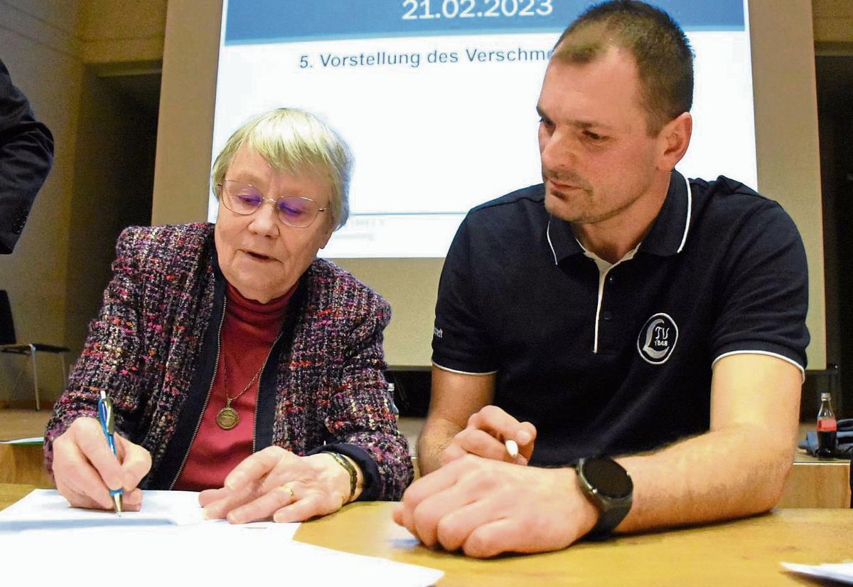 Unter lautem Beifall unterzeichneten Johanna Lütticke vom Vorstand des SV Aktiv Bad Westernkotten und Nikola Milosevic vom LTV Lippstadt im Beisein von Notar Josef Gudermann den Verschmelzungsvertrag. Foto: Giannakis