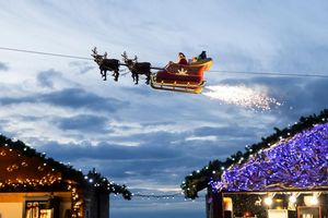 Ein Weihnachtsmann in einem fliegenden Schlitten ist in Montreux über den Weihnachtsständen vom Weihnachtsmarkt unterwegs. - Foto: Cyril Zingaro/KEYSTONE/dpa