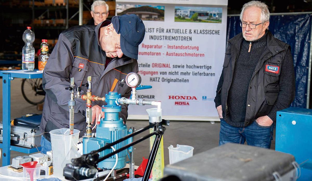 Konzentriert gibt Tüftler Detlef Gast (74) die Zutaten in seinen Versuchsaufbau: Diesel und Wasser. Im Messzylinder (Bildmitte) die gelbliche Diesel-Wasser-Emulsion für den 22 kW-Serien-Motor. Friedrich Dicke (r.), Inhaber des Anröchter Motorenfachbetriebs, schaut noch etwas skeptisch drein, aber der von ihm zur Verfügung gestellte Testmotor versieht klaglos den Dienst mit der ungewöhnlichen Kraftstoffmischung. Foto: Eickhoff