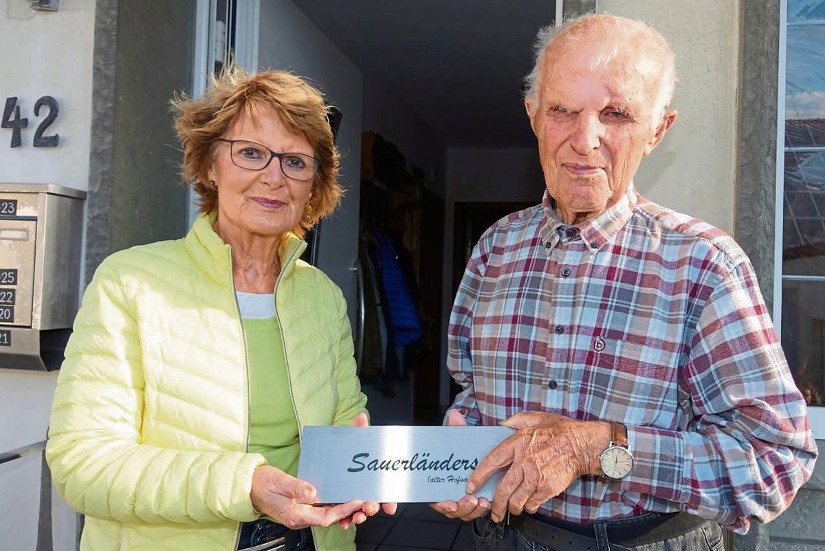 Die Koordinatorin des Projekts, Maria Dickhut, überreicht Leo Heinrich Rüther ein Schild mit der Aufschrift „Sauerländers“ – der frühere Hausname, bevor es stattdessen den Namen „Rüther“ gab. Fotos: Kloer