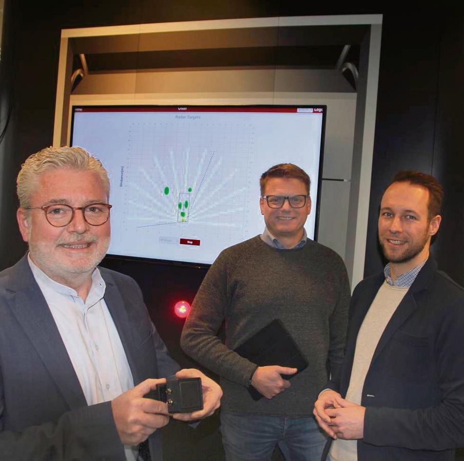 Vor einem angedeuteten Garagentor präsentieren (v.l.) Helmut Friedrich, Dirk Danzebrink und Nick Klause den neuen Radarsensor. Er erlaubt beispielsweise, das Schließen eines Tores angemessen zu verlangsamen – statt einfach nur zu stoppen. Foto: Schwade
