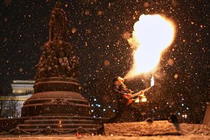 Heiß und kalt: Ein Straßenkünstler führt bei Schneefall eine Feuershow im russischen St. Petersburg auf. - Foto: Dmitri Lovetsky/AP/dpa