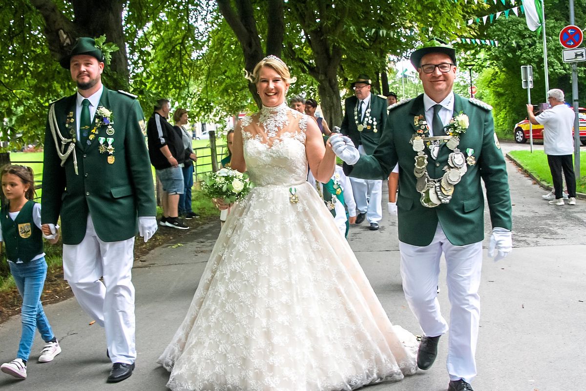 Das Königspaar Mathias und Anja Schüngel zog unter blauem Himmel durch die geschmückten Straßen. Die Königin in einer Robe aus elfenbeinfarbener Spitze zog dabei alle Blicke auf sich. Fotos: Wissing