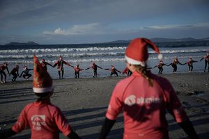 Mit Weihnachtsmannmützen verkleidete Menschen surfen während der «Papanoelada Surfera» (Surfer-Nikolaus-Aktion) am Strand von Patos. - Foto: Adrián Irago/EUROPA PRESS/dpa