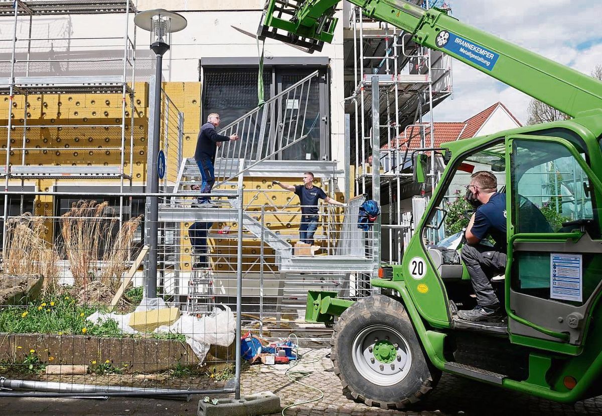Der Teleskoplader fährt langsam und vorsichtig ein Geländer-Element nach dem anderen an die Metalltreppe seitlich des Rathauses heran, wo sie an der passenden Stelle angebracht werden. Fotos: Bsdurek