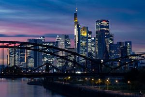 Die Lichter der Bankenskyline von Frankfurt leuchten in der Abendstimmung. - Foto: Boris Roessler/dpa