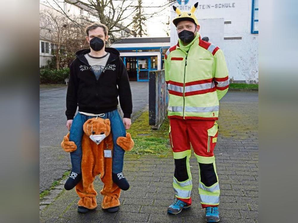 Dr. Teddy Bär trägt Impf-Koordinator Tim von Palubitzki, Jonathan Knischewski trägt das Pokemon Pikachu auf dem Kopf.