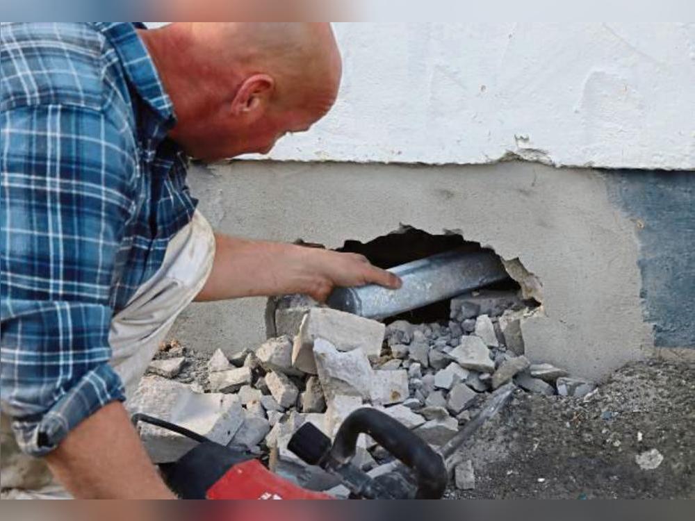 Mit einem Bohrhammer stemmte ein Bauarbeiter die Zeitkapsel im Betonsockel der Schule frei.