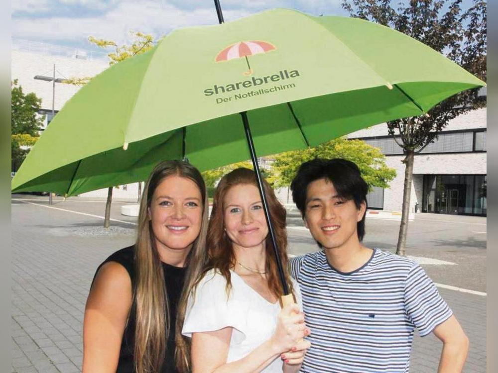 Die Leih-Regenschirme („Sharebrella“) sollen im Oktober in der Lippstädter City verfügbar sein. Das hoffen (v.l.) Anna Vanbrabant, Sara Massimo und Fuga Inui. Foto: Schwade
