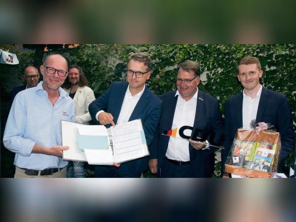 Was CDU-Generalsekretär Carsten Linnemann (2.v.l.) wohl lieber war? Tischlermeister Martin Tack gab ihm einen Ordner voll Bürokratie mit an die Hand, Markus Patzke (Stadtverband) und Michael Bals (MIT) „Süßes aus Lippstadt“ – extra in einer Holzkiste. Foto: Schwade