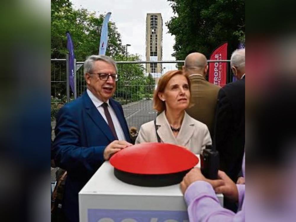 Bürgermeisterin Anne Voituriez am fiktiven Auslöseknopf vor dem Hochhaus.