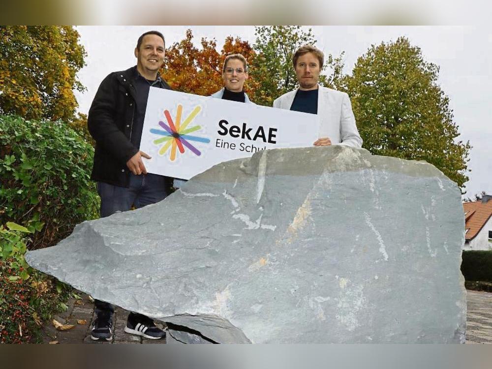 Wie schwer ist der Anröchter Grünsandstein? Das wollen v.l. Marktmeister Jens Becelewski, Denise Homann (Förderverein) und Schulleiter Matthias Bigge wissen. Foto: Ulrike Dietz