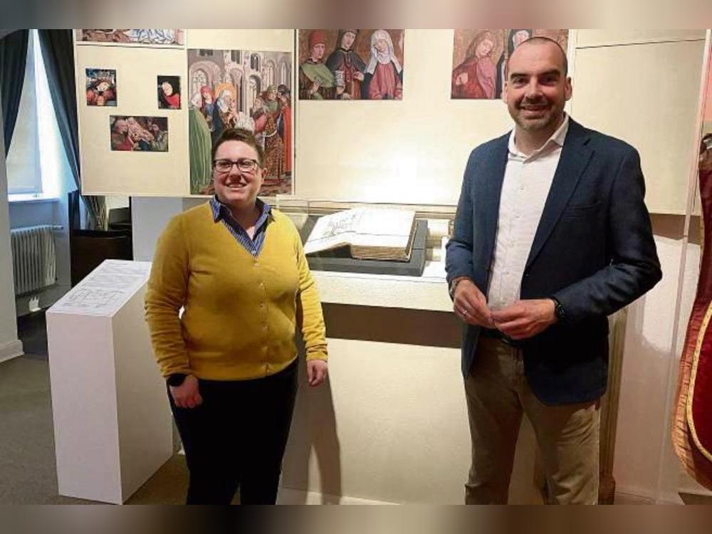 Kuratorin Yvonne Püttmann und Museumsleiter Dr. Sebastian Steinbach vor einer Visualisierung des Liesborner Altars. In der Mitte: Bernhard Wittes „Historia Westphaliae“. Foto: Dierk Hartleb