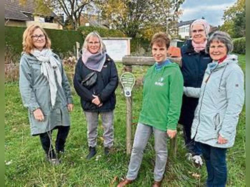 Das Foto zeigt Mitglieder des Teams vom Naturgarten Lippstadt Nord und des BUND Lippstadt/Erwitte vor dem aufgestellten Schild „Zum Schutz der vielen Arten brennt nachts kein Licht in diesem Garten“.