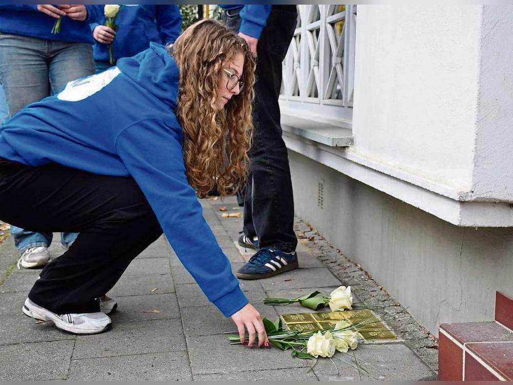 Sieben weiße Rosen legten die Schüler an den Stolpersteinen für die Familie Cohn/Schiff in der Cranestraße 42 nieder. Foto: Daniel Kossack