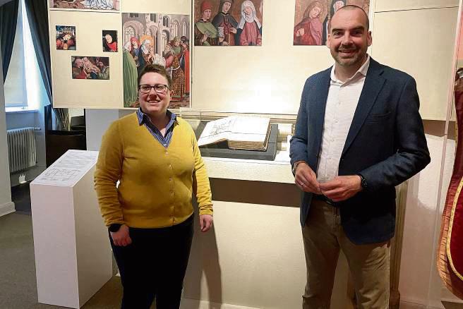 Kuratorin Yvonne Püttmann und Museumsleiter Dr. Sebastian Steinbach vor einer Visualisierung des Liesborner Altars. In der Mitte: Bernhard Wittes „Historia Westphaliae“. Foto: Dierk Hartleb