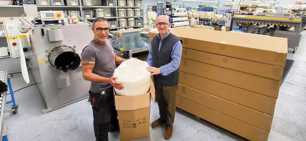 Die Roll-Pack-Anlage für Matratzen, hier gezeigt von Yacoub Gharib und Florian Kleinehollenhorst, reduziert das Versandvolumen um satte 60 Prozent gegenüber der herkömmlichen Verpackungsweise (rechts im Bild). Foto: Axel Schwade