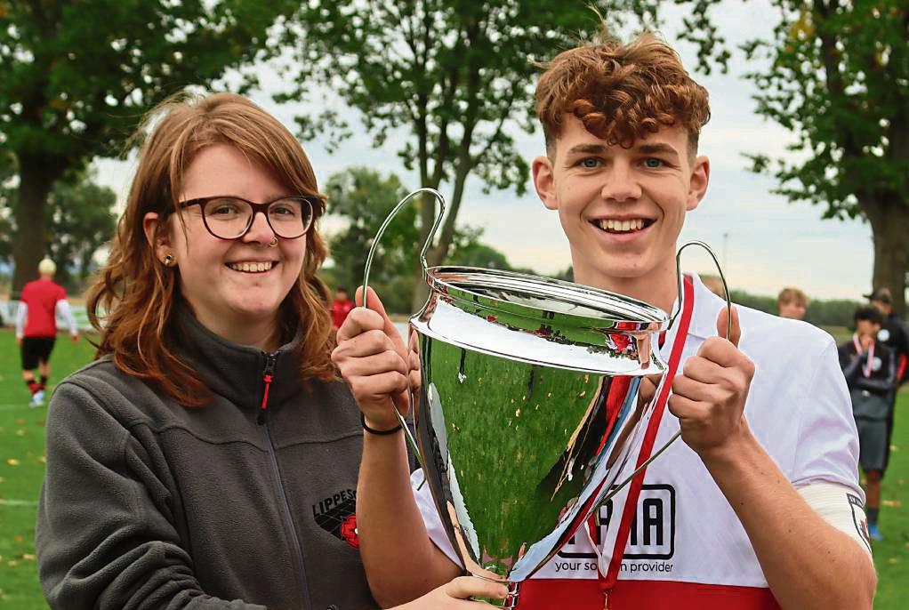 Katharina Fromm (l.) vom Sponsor Lippe-Solar überreichte Lippstadts Kapitän Daniel Zimbelmann den Pokal. Der Westfalenligist sah sich im Endspiel einer tapfer kämpfenden Jugendspielgemeinschaft Suttrop/Belecke/Kallenhardt/Hirschberg gegenüber. Fotos: Uwe Feichtinger