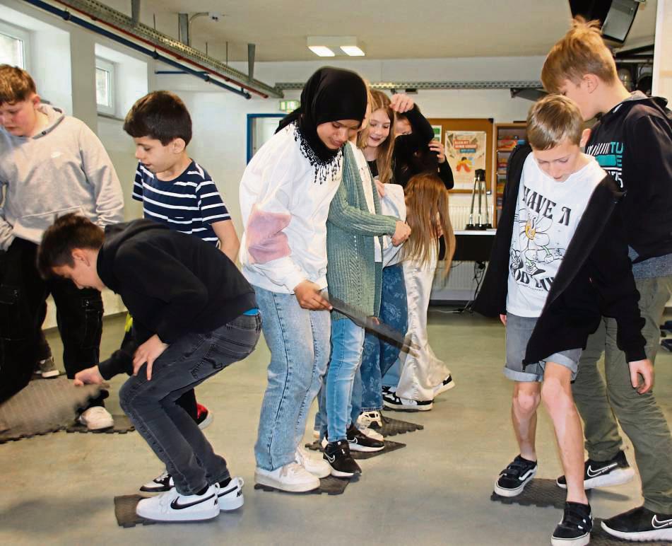 Teamgeist ist beim Spiel „Flussüberquerung“ gefragt. Nur zusammen können die Schüler der Klasse 5b der Sekundarschule Anröchte-Erwitte die Aufgabe lösen. Foto: Meschede