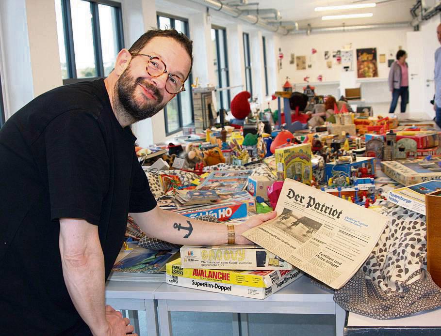 Claus Richter präsentiert auf einem riesigen Tisch Erinnerungsstücken und Spielzeug aus seiner Kindheit. Dazu gehört auch eine Patriot-Ausgabe von 1982. Vor allem sein Vater habe dafür gesorgt, dass diese Dinge aufgehoben wurden, sagt der Künstler. Fotos: Wissing