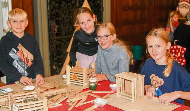 Nathanael (l.) baut an diesem Tisch, gemeinsam mit anderen Kindern, dekorative Windlichter aus Holz.