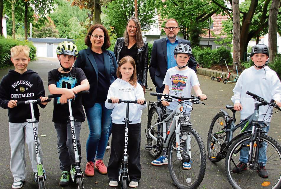 Schüler der Pankratius-Grundschule (vorne) sowie die Schulmobilitätsbeauftragte Petra Henke, Schulleiterin Sonja Kleine und Bürgermeister Alfred Schmidt (hinten, v.l.) freuen sich darüber, dass sie bald neue Fahrradständer für Roller und Räder erhalten. Foto: Meschede