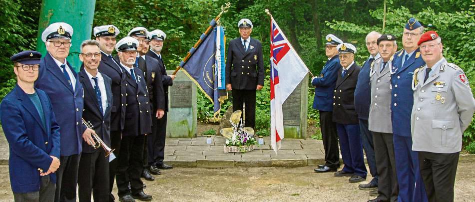Mitglieder des Marinevereins und der Reservistenkameradschaft stehen vor dem Ehrenmal am Marineheim. Heinz-Werner Strube (Mitte) hielt eine berührende Rede. Foto: Wissing