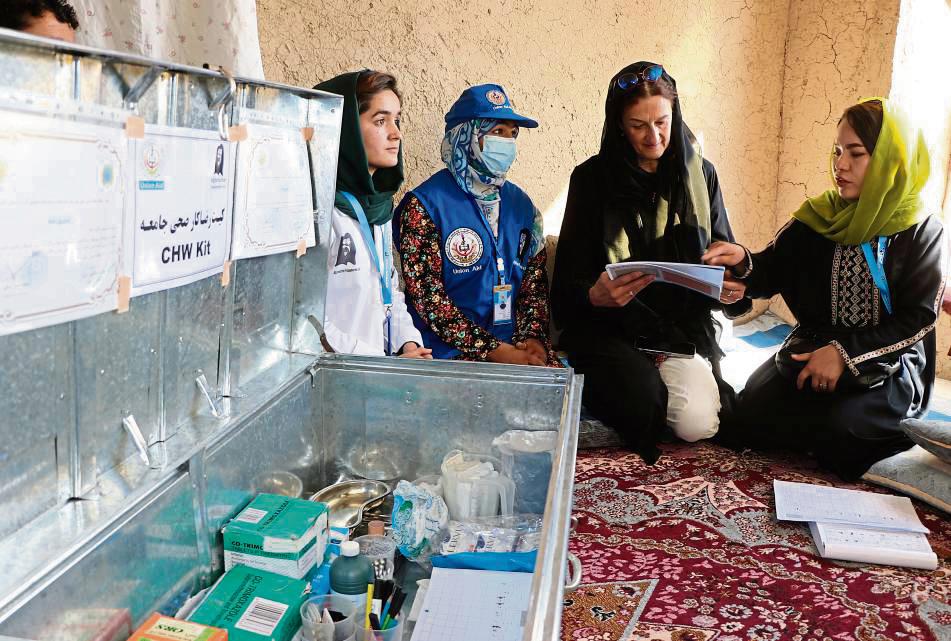 Jede Dorfgesundheitshelferin (blaue Kappe) empfängt täglich etwa fünf Kranke aus ihrem Dorf, führt wöchentliche Hausbesuche bei chronisch Erkrankten und Schwangeren im Dorf durch, überweist und begleitet Erkrankte mit Arztbedarf an die Klinik.