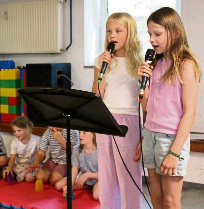 Pia und Lena (rechts) singen das Lied „Wellerman“, während die anderen Kindern mit ihren Bechern den passenden Rythmus vorgeben. Foto: Mintert