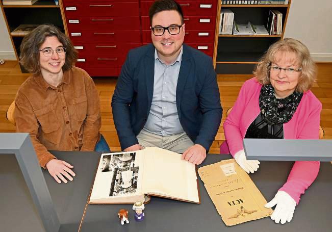 Schlagen am 18. Mai für die Führungen durch das Kreisarchiv unter anderem das Album mit Fotos auf, die den Besuch von Queen Elisabeth II. mit Prinzgemahl Philip 1965 in Soest dokumentieren: (v. l.) Kira Knappkötter, Maximilian Fahrenbach und Iris Zwitzers vom Kreisarchiv. Foto: Schulte-Nölle (Kreis Soest)
