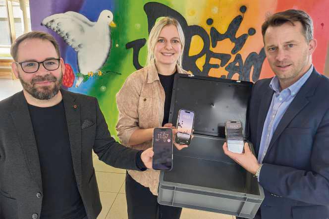 Wenn das Smartphone in eine Tresor-Kiste im Klassenraum kommt, können sich Schüler besser konzentrieren: Diese Erkenntnis aus einem Experiment erläuterten jetzt (v.l.) Prof. Sven Lindberg und Doktorandin Jeanette Skowronek dem Lippstädter Gesamtschul-Leiter Jan Haurand. Foto: Axel Schwade