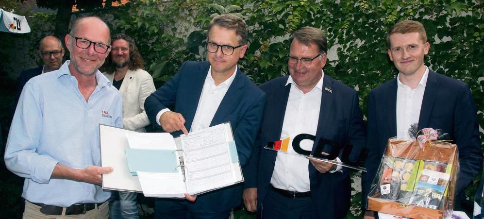 Was CDU-Generalsekretär Carsten Linnemann (2.v.l.) wohl lieber war? Tischlermeister Martin Tack gab ihm einen Ordner voll Bürokratie mit an die Hand, Markus Patzke (Stadtverband) und Michael Bals (MIT) „Süßes aus Lippstadt“ – extra in einer Holzkiste. Foto: Schwade