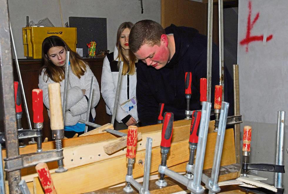 In der Werkstatt: Vogelbauer Frederik Lauber zeigt Lotta Johannsmann und Amy Quante, wie die Flügel gefertigt werden. In diesem Jahr baut Frederik vier Vögel für das Jubiläum des Schützenvereins Dedinghausen.