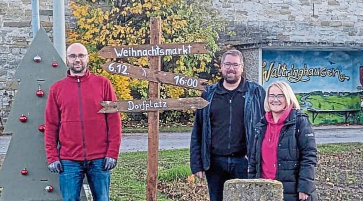 In Waltringhausen sind vom Verein „Waltringhausen Aus Sympathie“ Schilder für den siebten Weihnachtsmarkt 2025 montiert worden, zu sehen sind (v.l.) Emanuel Aßhoff, Alexander Koch und Anja Pöppelbaum. Foto: Reinhard Priesnitz