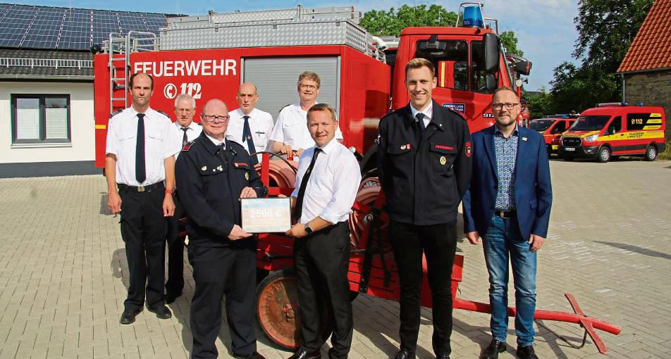 2500 Euro für einen neuen Geräteschuppen: Nico Heiderich überreichte Philipp Tillmann den Spendenscheck. Mit ihnen freuten sich (hinten v.l.) Vize-Wehrleiter Hendrik Scholz, Jörg Vätter und Walter Brinkhoff (Löschzug 2), Kreisbrandmeister Thomas Wienecke sowie Vize-Löschgruppenführer Gregor Graskemper und Bürgermeister Alfred Schmidt.