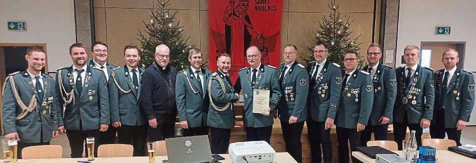 Oberst Patrick Will überreicht Karl-Josef Beiteke die Urkunde zum Ehrenvorsitzenden, umrahmt vom gesamten Vorstandsteam der St. Nikolaus Schützenbruderschaft. Foto: Thomas
