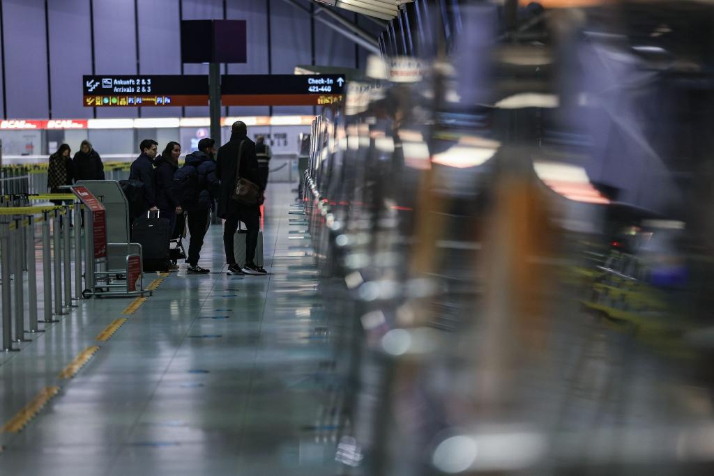 Reisende stehen am Flughafen Köln/Bonn vor einem Schalter. - Foto: Oliver Berg/dpa