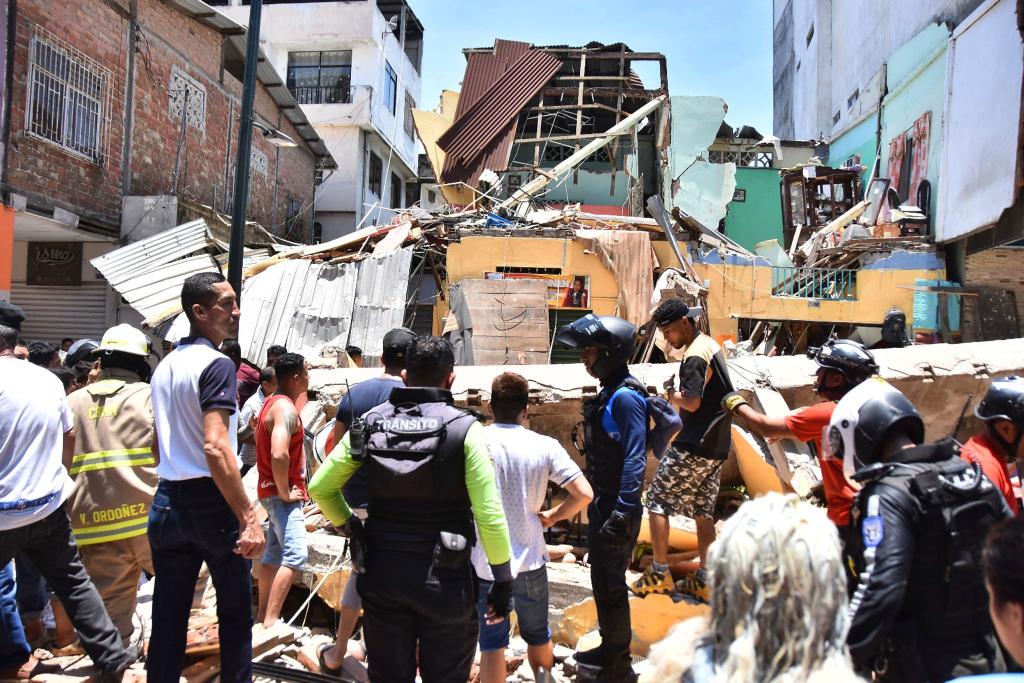 Anwohner und Rettungskräfte stehen vor zerstörten Gebäuden in Machala. - Foto: Jorge Sanchez/AP/dpa