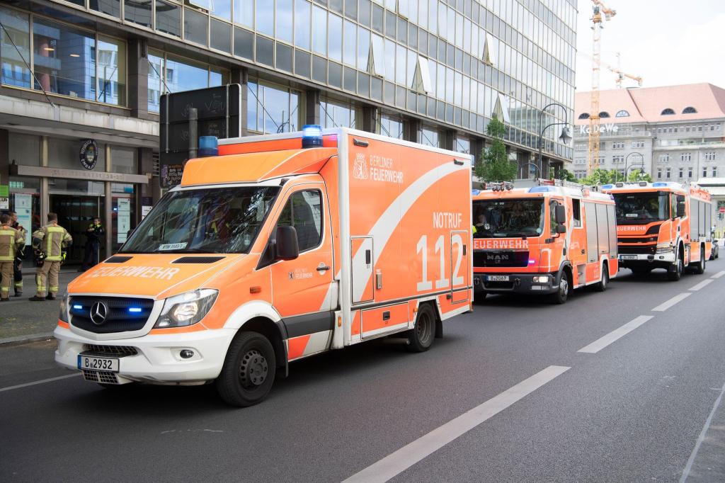 Einsatzfahrzeuge der Feuerwehr stehen vor dem mehrgeschossigen Gebäude, in dem es zu einem tödlichen Unfall mit einem Paternoster gekommen war. - Foto: Paul Zinken/dpa