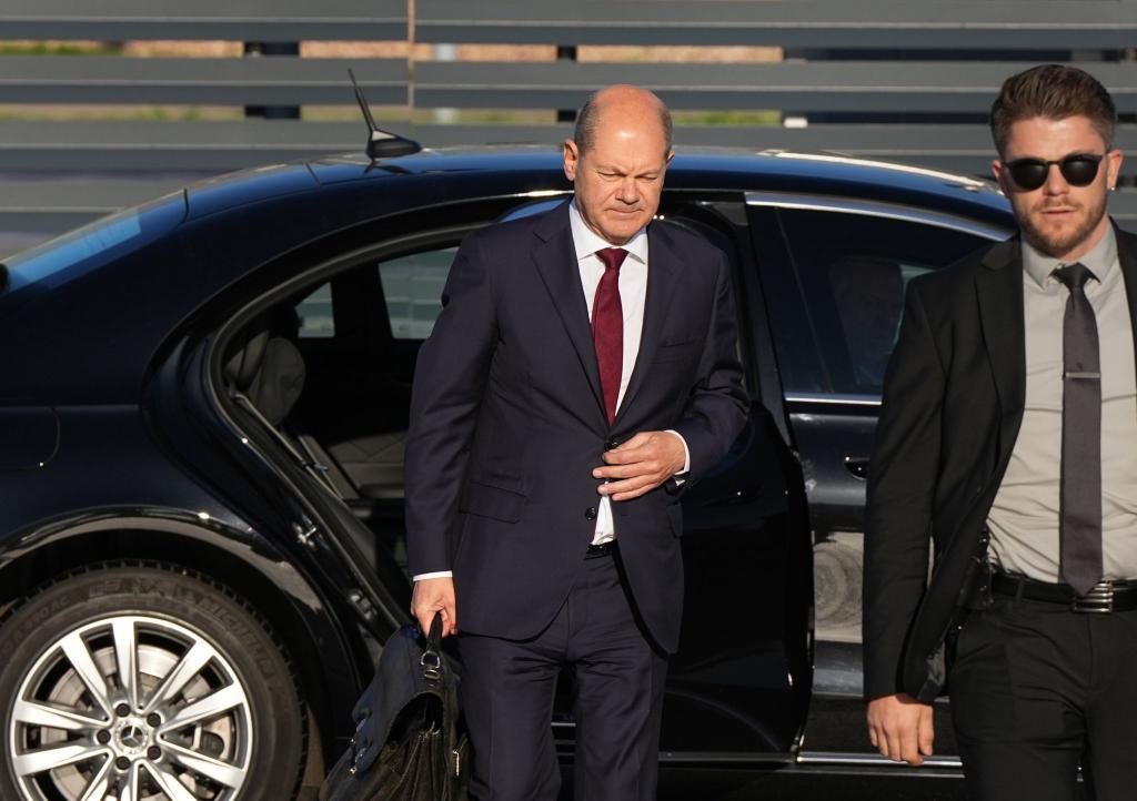 Bundeskanzler Olaf Scholz (l, SPD) kommt zum Start einer zweitägigen Reise auf dem militärischen Teil des Flughafens Berlin Brandenburg BER an und steigt aus einer Limousine. - Foto: Soeren Stache/dpa