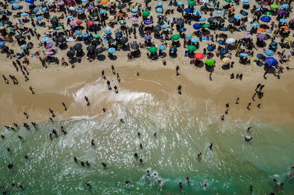 Strandbesucher strömen an den Strand von Ipanema, um der extremen Hitze in Brasilien zu entkommen. - Foto: Bruna Prado/AP//dpa