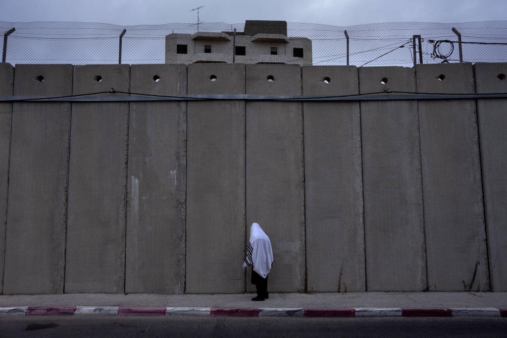 Ein ultraorthodoxer jüdischer Mann betet während des jüdischen Feiertags «Sukkot» (Laubhüttenfest) in Bethlehem neben der von Israel errichteten Trennmauer, die das Rahelgrab schützen soll. - Foto: Oded Balilty/AP/dpa
