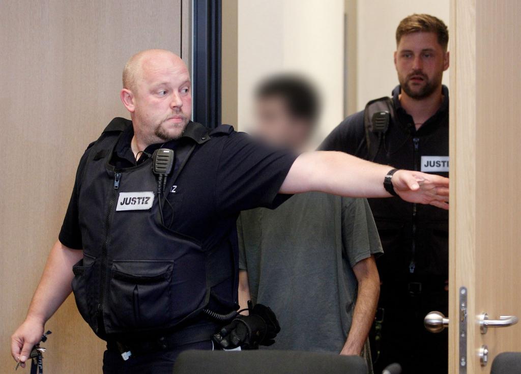 Der Hauptangeklagte wird von Justizbeamten in den Gerichtssaal geführt. - Foto: Roland Weihrauch/dpa