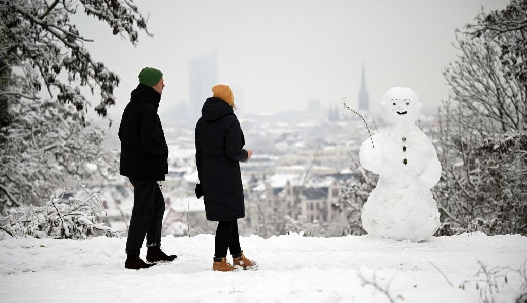 Zwei Spaziergänger wandern am Fockeberg (Leipzig) an einem Schneemann vorbei. - Foto: Patricia Bartos/dpa