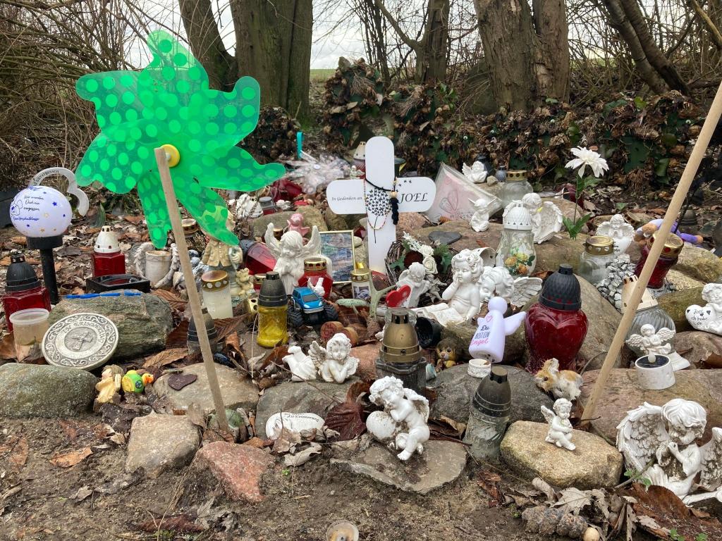 Engelsfiguren und Erinnerungsstücke stehen nahe der Stelle, wo Joel am 14. September 2023 mit Stichverletzungen gefunden wurde. - Foto: Christian Johner/dpa