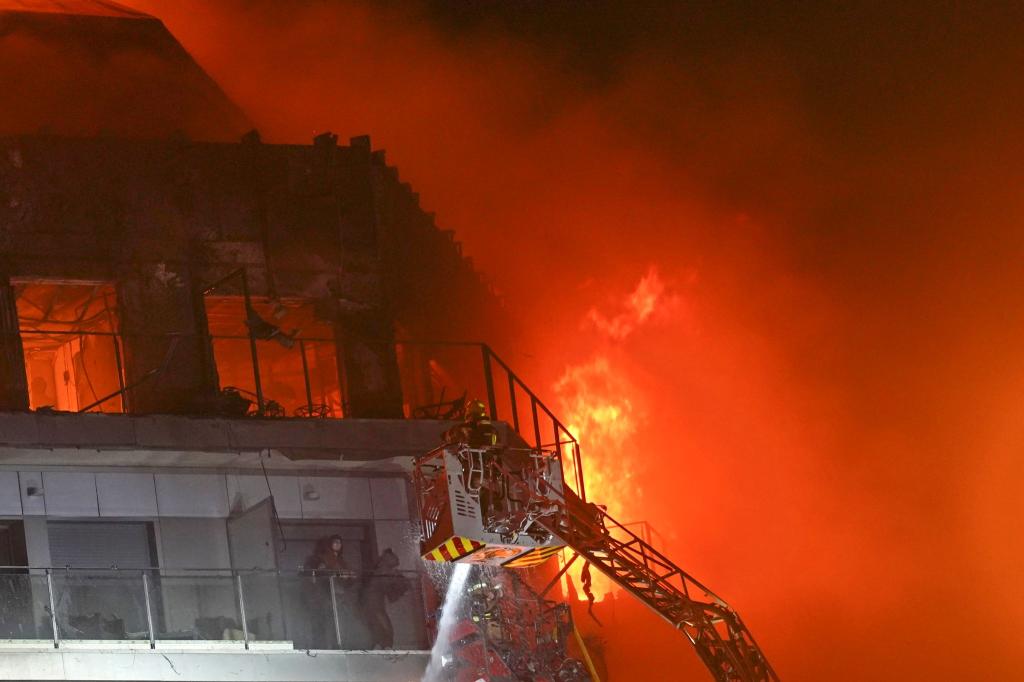Feuerwehrleute retten zwei Menschen aus dem brennenden Hochhaus. - Foto: Alberto Saiz/AP/dpa