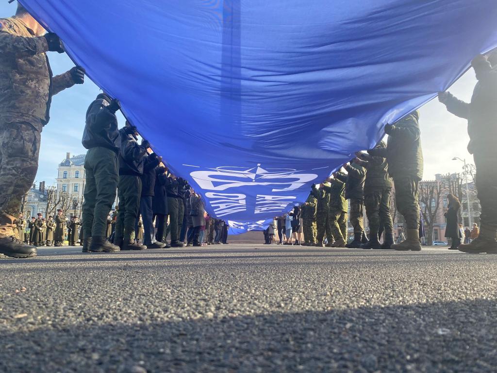Ein riesige blaue Fahne mit der Aufschrift «Latvija Nato 20» wird vor dem Freiheitsdenkmal entrollt. Lettland feiert 20 Jahre Nato-Mitgliedschaft. - Foto: Alexander Welscher/dpa